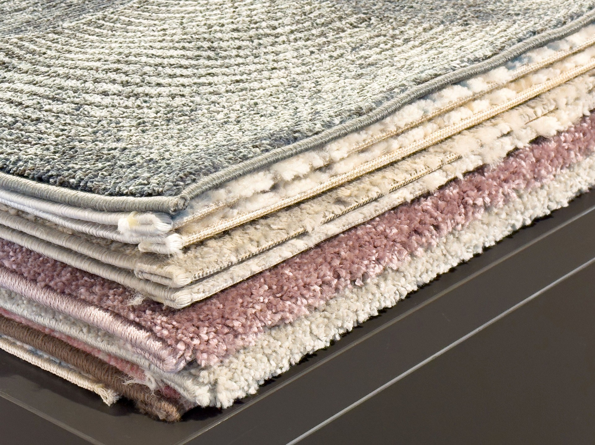 Stack of layered textured carpets with varied patterns and colors for interior design